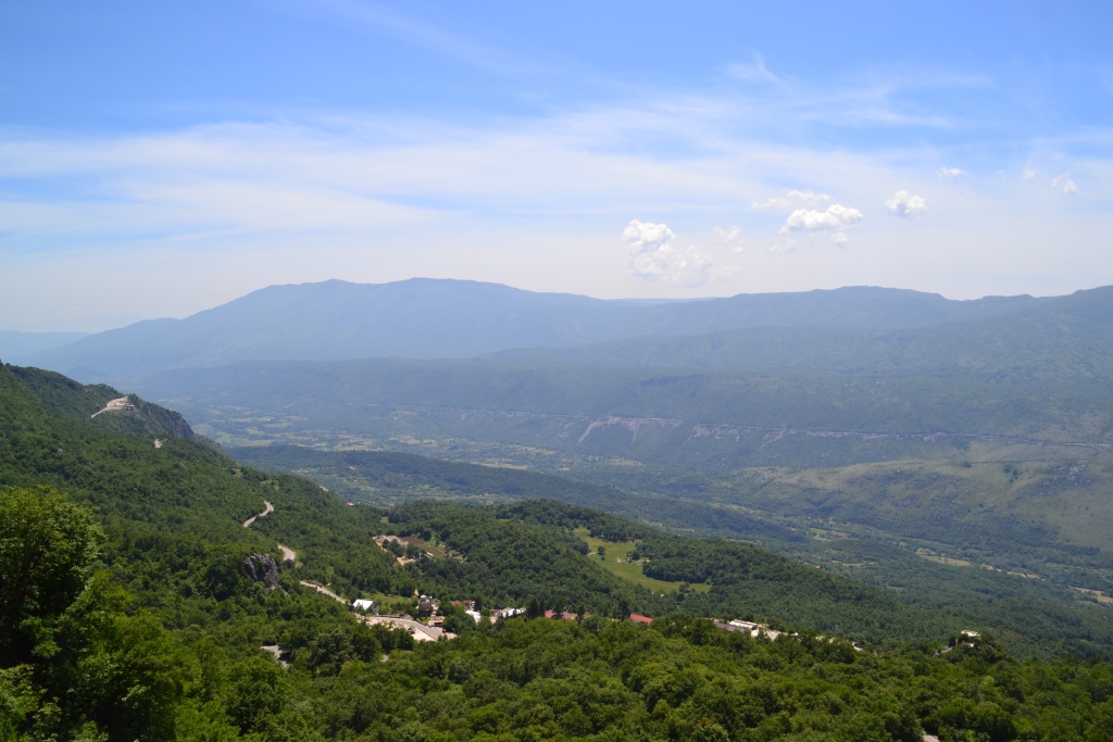 Forested mountain ridges and valleys seen from a winding road in Montenegro.