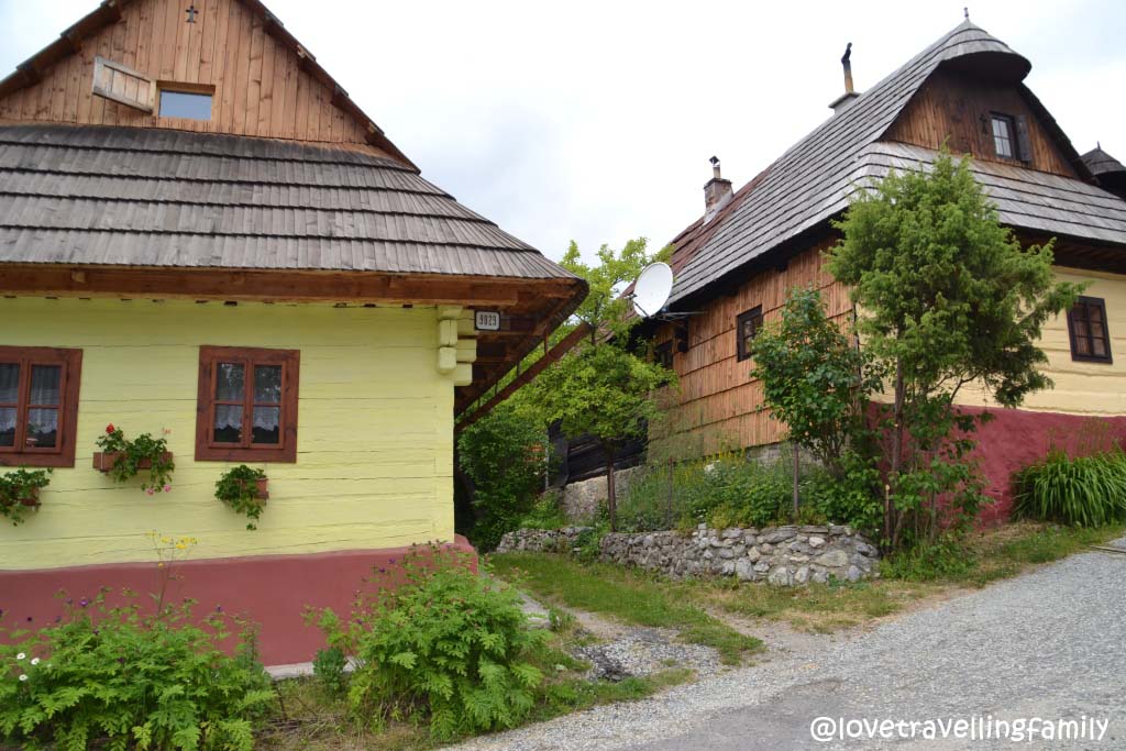 Pink and yellow painted wooden houses with steep roofs in Vlkolínec.